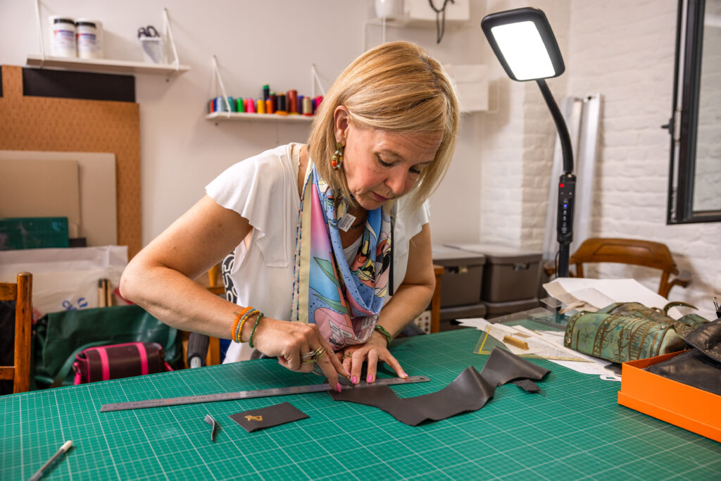 An Vandenberk holding a bespoke leather bag in her Brussels atelier